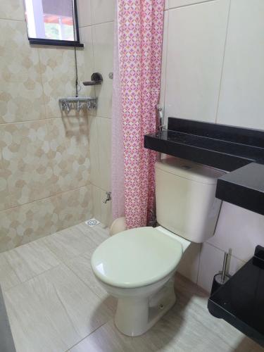 a bathroom with a toilet and a pink shower curtain at Studio Mara Alagoa in Alagoa