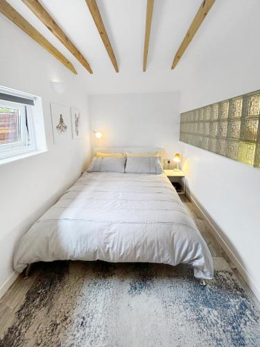 a bedroom with a large bed in a white room at Modern self contained tiny home with patio in Loughton