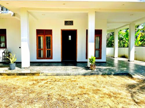 a white house with red doors and a yard at Lotus villa in Matara
