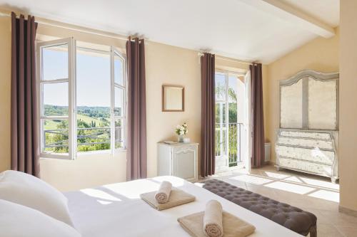 a bedroom with a large bed and large windows at Saint-Tropez Golf Residences in Saint-Tropez