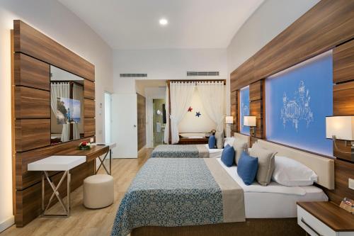 a hotel room with two beds and a desk at Limak Atlantis Deluxe Hotel Belek in Belek