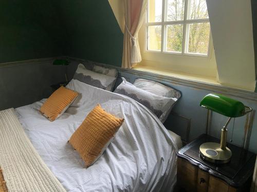 a bedroom with a bed with pillows and a window at Le Castel Ecossais in Senlis