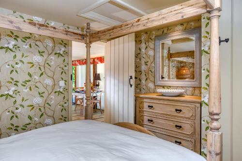 a bedroom with a bed and a dresser with a mirror at Harts Leap in Redmarley DʼAbitot