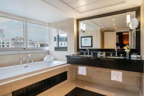 a bathroom with a tub and a large mirror at Warwick Paris Champs-Elysées in Paris