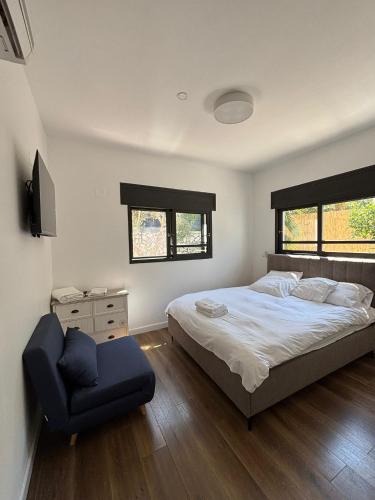 a bedroom with a bed and a chair in it at Habait ba Shomera in Shomera