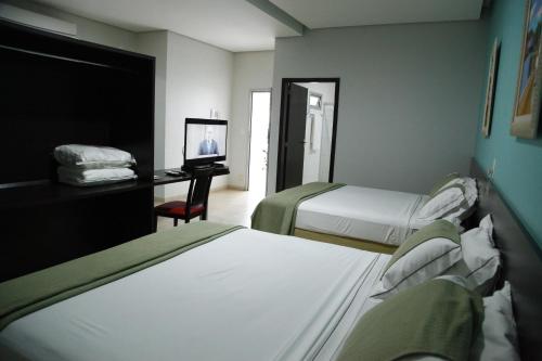 a hotel room with two beds and a desk with a television at Porto Center Hotel in Luís Eduardo Magalhães