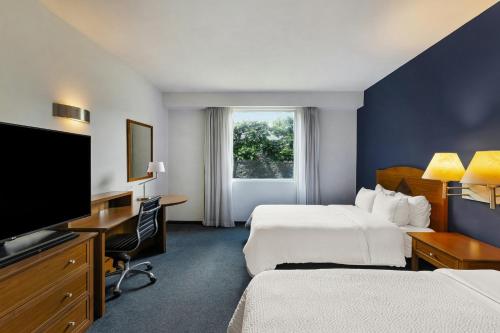 a hotel room with two beds and a flat screen tv at Fiesta Inn Express San Luis Potosí Oriente in San Luis Potosí