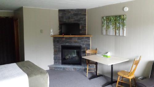 a room with a fireplace and a table and a bed at The Spirit Rock Outpost & Lodge in Wiarton