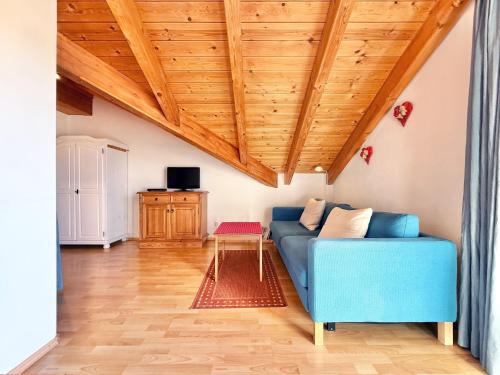 a living room with a blue couch and wooden ceilings at Sonnenhof Seeg 17 in Seeg