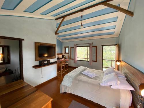 a bedroom with a large bed and a tv at Chalé Serra dos Encantos in Lavras Novas