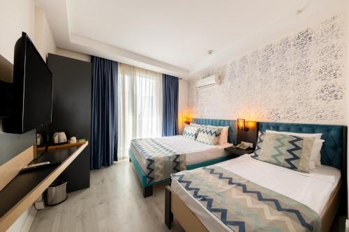 a hotel room with two beds and a tv at Palmora Lara Hotel in Aksu