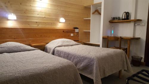 a bedroom with two beds and a wooden wall at Hotel Glaizette in LʼArgentière-la-Bessée