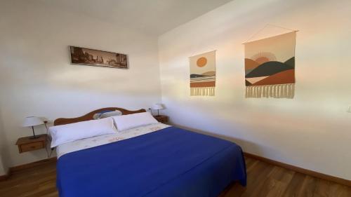 a bedroom with a blue bed and paintings on the wall at El Chorro Atico in Calera