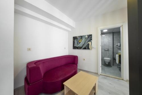 a living room with a purple couch and a table at Palmora Lara Hotel in Aksu
