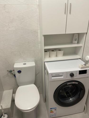 a bathroom with a toilet and a washing machine at Happy apartment 1 in Roşu