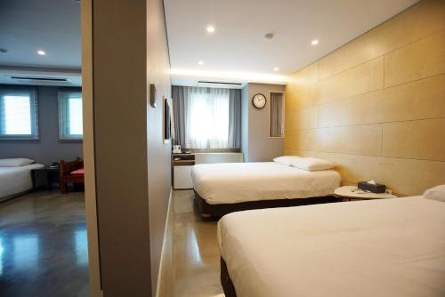 a hotel room with two beds and a clock on the wall at Hotel Dada Gyeongbokgung in Seoul