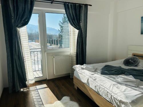 a bedroom with a bed and a large window at Green Apartaments Self Check-In 24-7 Free Parking in Zărneşti