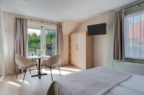 a bedroom with a bed and a table and chairs at Appartementen Parkzicht in Bergen aan Zee