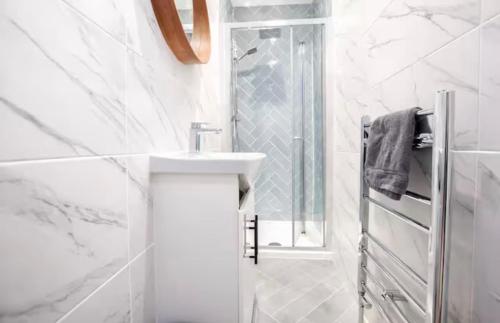 a white bathroom with a sink and a shower at Portside Apartment in Greenock