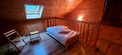 a room with a bed and a chair in a cabin at Les Chalets du Choumeau in Saint-Léger-les-Mélèzes
