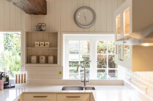 a kitchen with a sink and a clock on the wall at Tapnell Manor At Tapnell Farm in Yarmouth