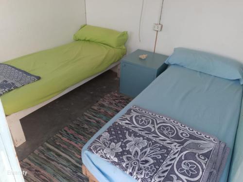 a small room with two beds and a night stand at Hamata House Camp in Abū Ghuşūn