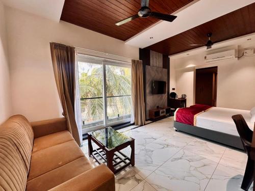 a bedroom with a bed and a couch and a window at Casa Marina Beachfront Resort in Padubidri