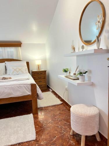 a bedroom with a bed and a mirror and a stool at Maria apartment in Ponta do Sol