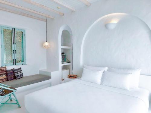 a white bedroom with a bed and a chair at Resort de Paskani in Hua Hin