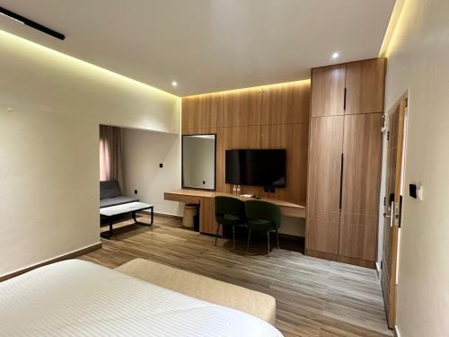 a hotel room with a bed and a desk and a television at Hamsun Shahrah-e-Faisal Extension in Karachi