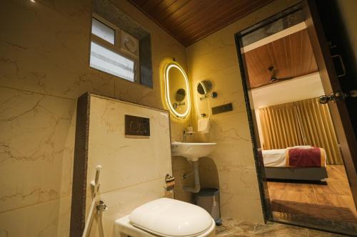a bathroom with a toilet and a sink and a mirror at Casa Marina Beachfront Resort in Padubidri