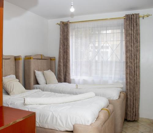 three beds in a room with a window at Cozy urban homes in Nakuru