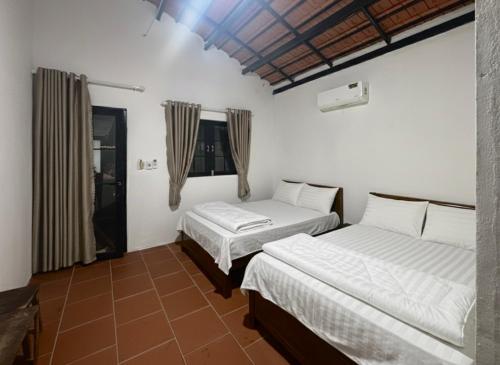 two beds in a room with white walls at Nhà Vườn - Garden homes in Ấp Bến Ké (2)