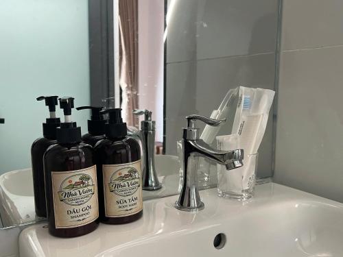 a bathroom sink with two bottles of soap and a mirror at Nhà Vườn - Garden homes in Ấp Bến Ké (2)