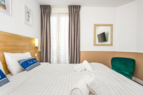 a hotel room with a bed and a green chair at Hotel Parisien in Menton