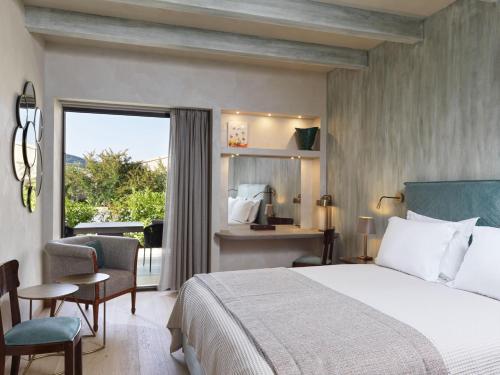 a bedroom with a bed and a desk and a window at Semeli Estate Suites in Koútsion