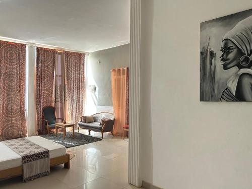 a living room with a bed and a painting of a woman at Jozene House in Ngaparou
