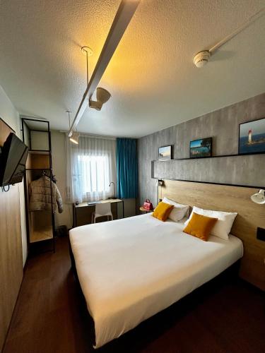 a hotel room with a large white bed with yellow pillows at ibis Saint-Malo Madeleine in Saint Malo