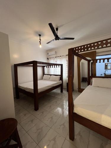 a bedroom with two beds and a ceiling fan at Casa Yangu in Watamu