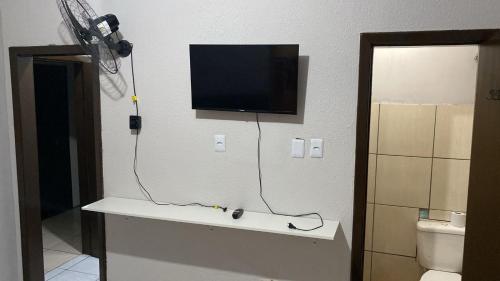 a tv on the wall of a bathroom with a toilet at Mega Hotel in Cascavel