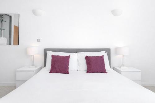 a white bed with two purple pillows and two lamps at Roomspace Serviced Apartments - Chorus in London