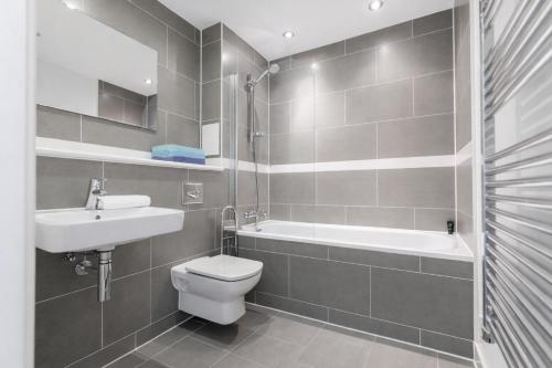 a bathroom with a toilet and a sink and a tub at Roomspace Serviced Apartments - Chorus in London