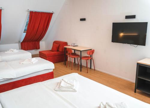 a room with two beds and a table and a tv at Bed and Breakfast Portal in Ljubljana