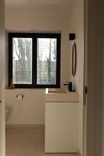 a white kitchen with a sink and a window at Stories Lodewijk en Margaretha in Bruges