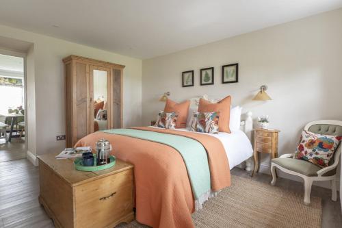 a bedroom with a bed with an orange blanket and a chair at Greenhead Cottage in Kelso