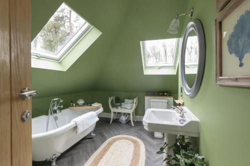 a green bathroom with a tub and a sink at Greenhead Cottage in Kelso