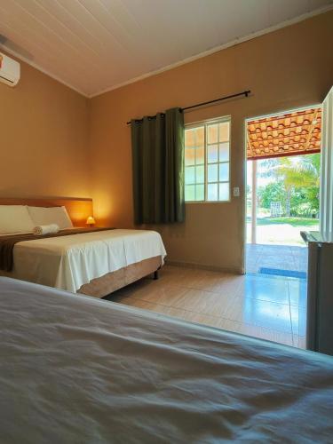 a bedroom with two beds and a large window at Pousada Sítio Rupestre Peruaçu in Januária