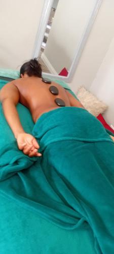 a shirtless woman laying on a bed with a blanket at Epic touch B&B in Sandton