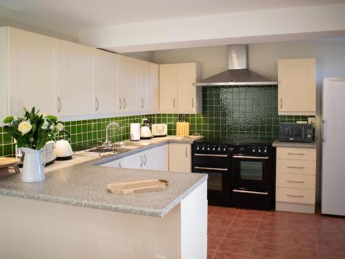 a kitchen with white cabinets and black appliances at Whitehouse Farm in Hartington