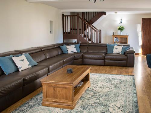 a living room with a brown leather couch and a coffee table at Whitehouse Farm in Hartington